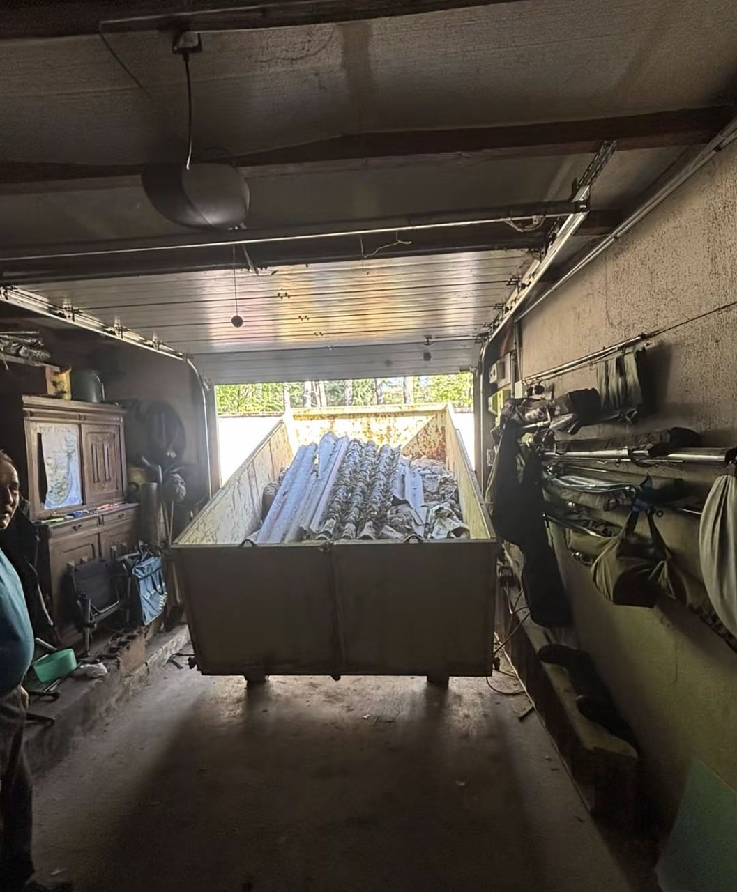 Benne 8 m³ grise remplie de gravats dans un garage en cours de travaux